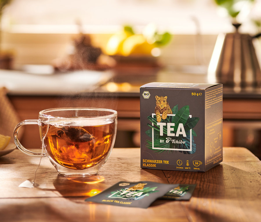 Filiżanka herbaty obok opakowania BIO TEA by Tchibo Klasyczna 8x20x2,5 g.