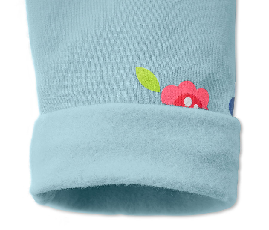 Detal spodni dresowych w kolorze jasnoniebieskim z kwiatowym wzorem i podwiniętym brzegiem.