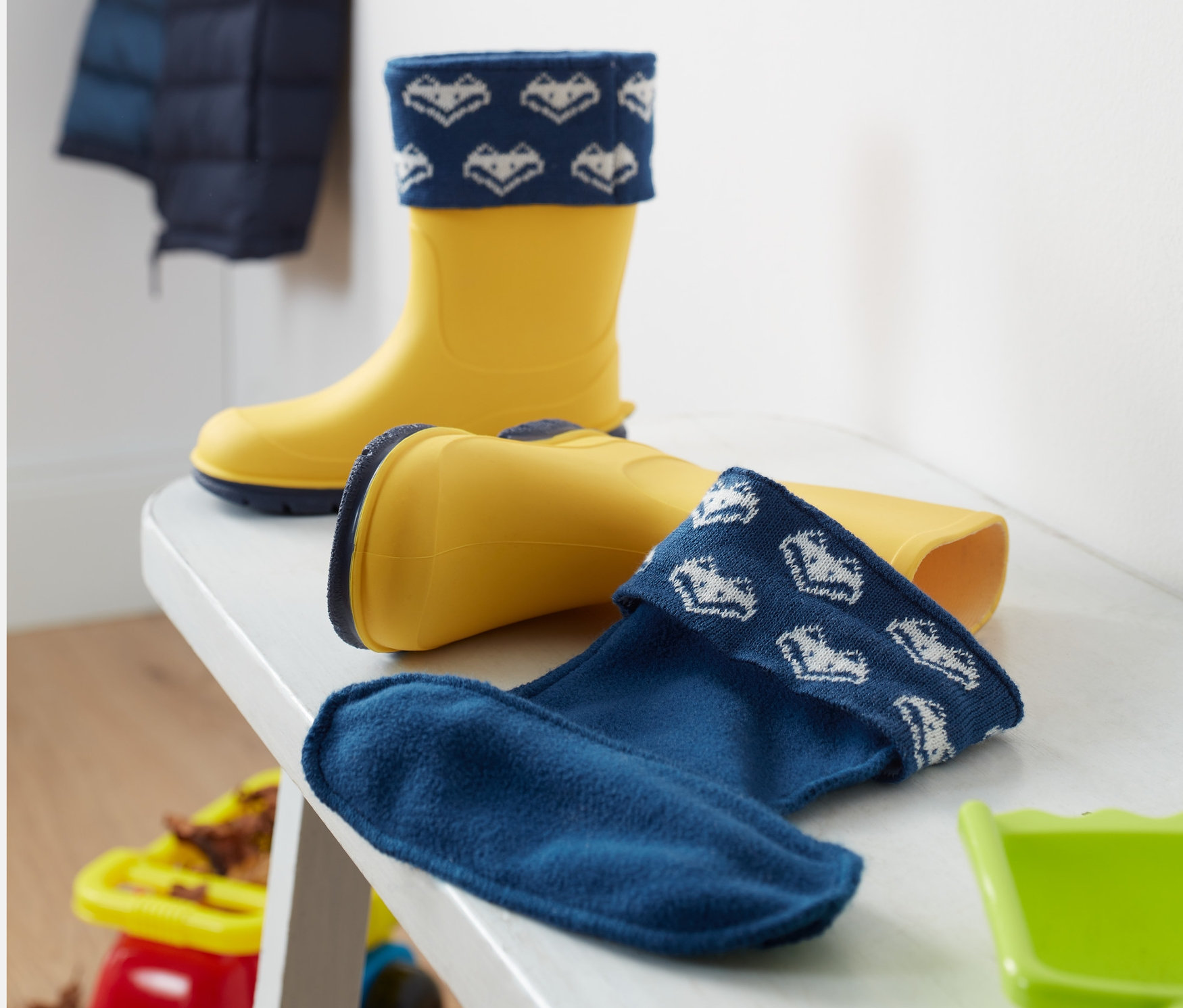 Żółte kalosze z wkładkami do kaloszy na białej ławce.