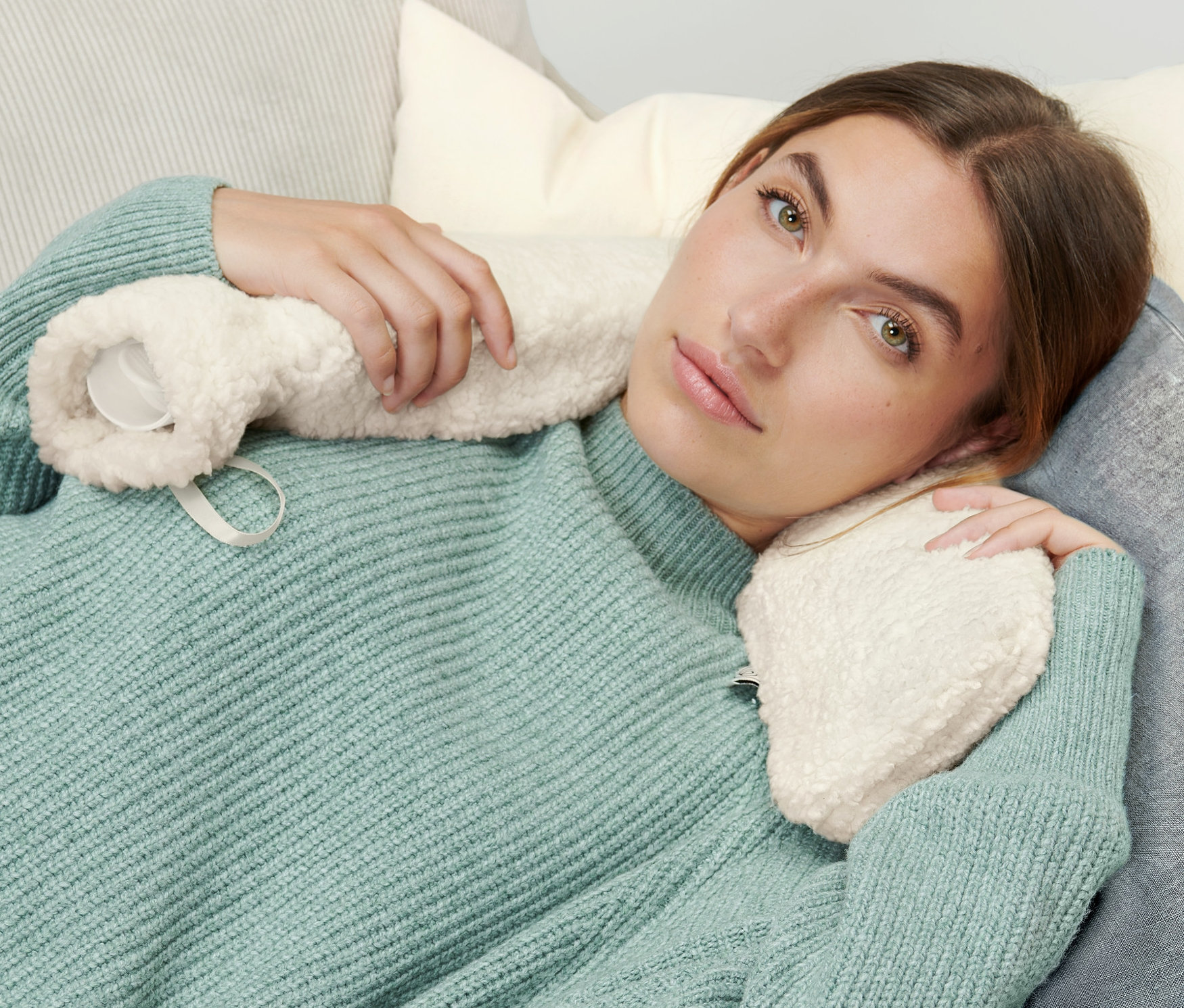 Kobieta leży na kanapie z długim termoforem.