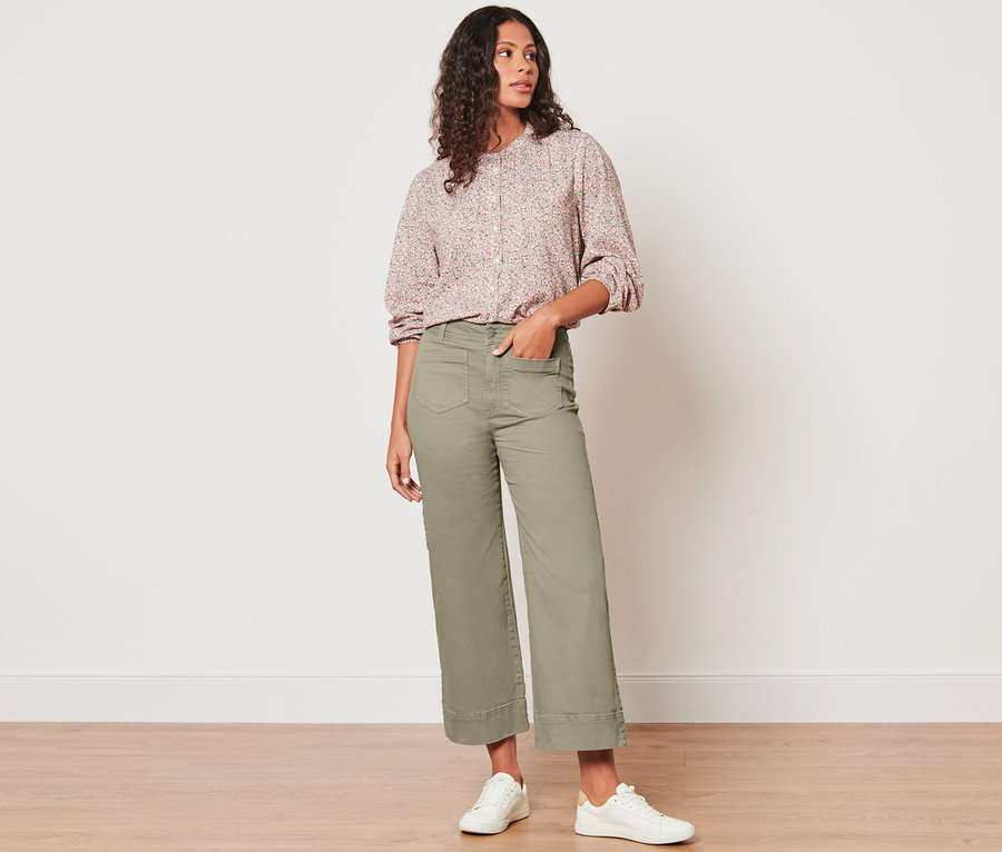 Kobieta stoi i pozuje w spodniach dżinsowych.