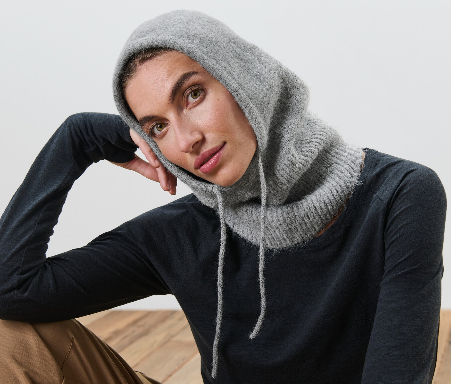 Kobieta pozuje w dzianinowym kapturze z kołnierzem.