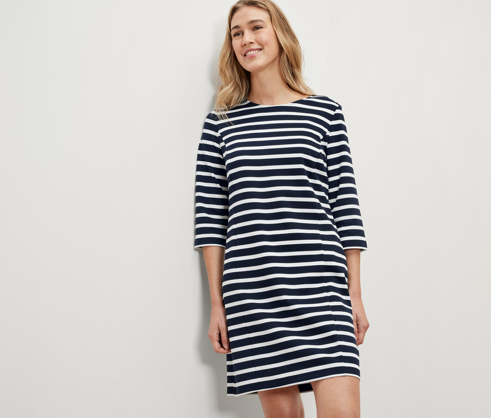 Blondynka w sukience dresowej w paski.