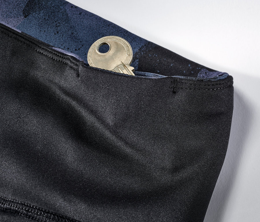 Zbliżenie na dwustronne legginsy sportowe w kolorze czarnym i granatowym z kluczem w kieszeni.