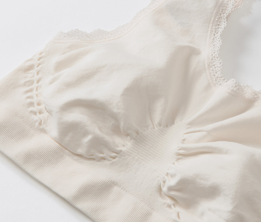 Zbliżenie na kremową, bezszwową braletkę z koronkowym wykończeniem.