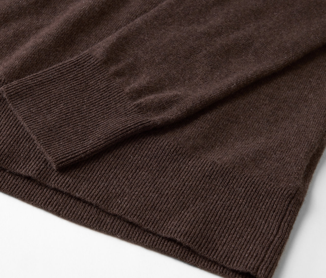 Szczegół brązowego swetra z długim rękawem.