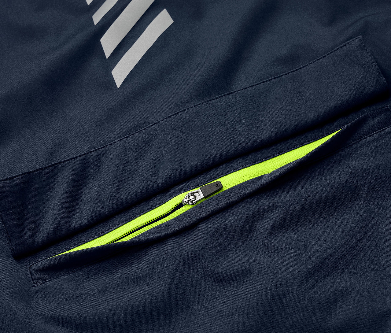 Szczegół niebieskiej kurtki przeciwdeszczowej Rad-Regenjacke z neonowo-zielonym zamkiem błyskawicznym przy kieszeni i elementami odblaskowymi.