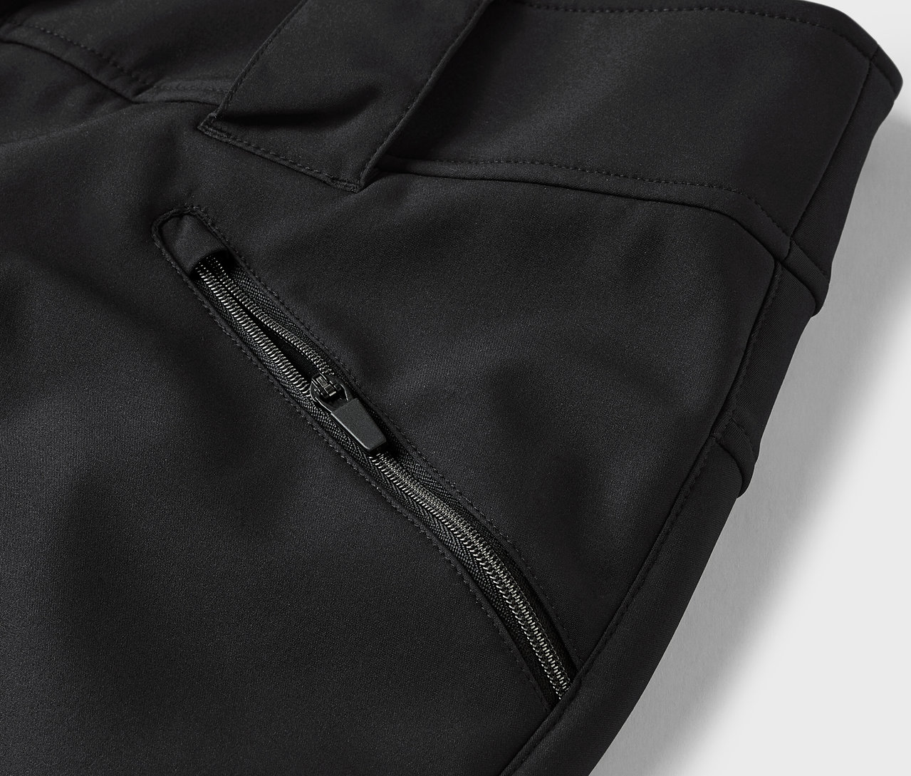 Szczegół czarnych spodni z kieszenią na zamek błyskawiczny.