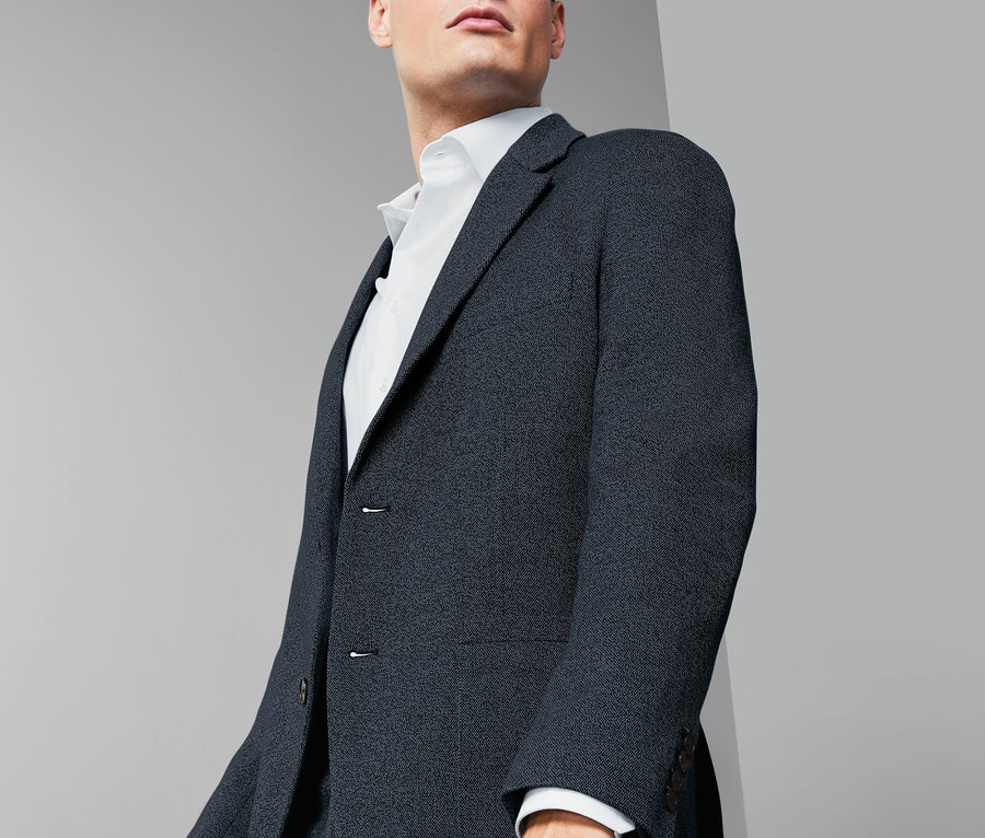 Mężczyzna w granatowej marynarce z dżerseju i białej koszuli.