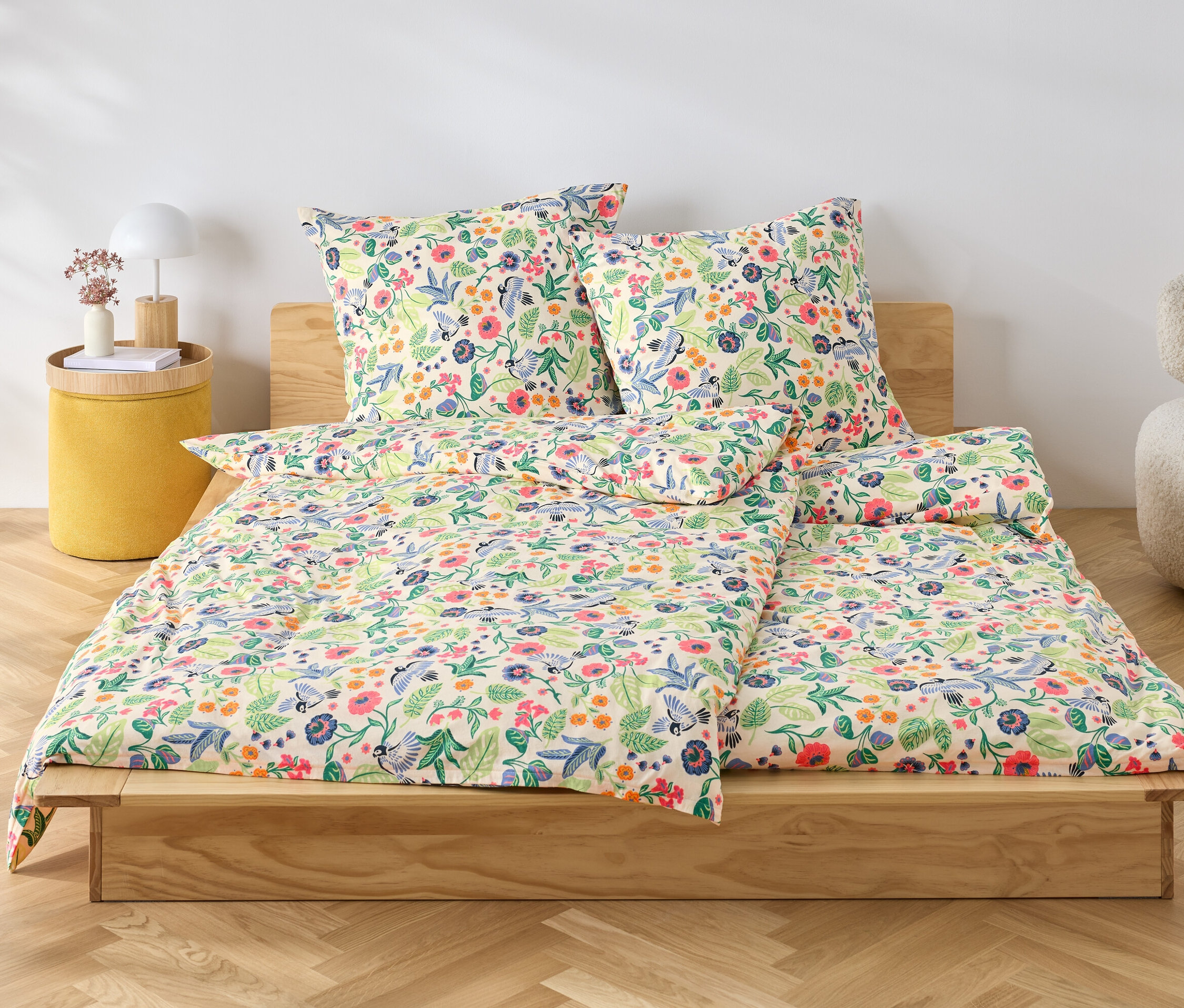 Na drewnianym łóżku leży pościel dżersejowa w kwiaty.