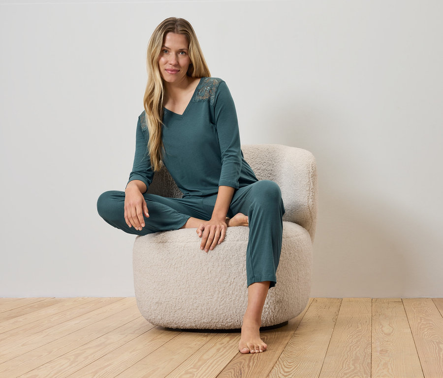 Kobieta siedzi na puszystym krześle w zielonej piżamie.