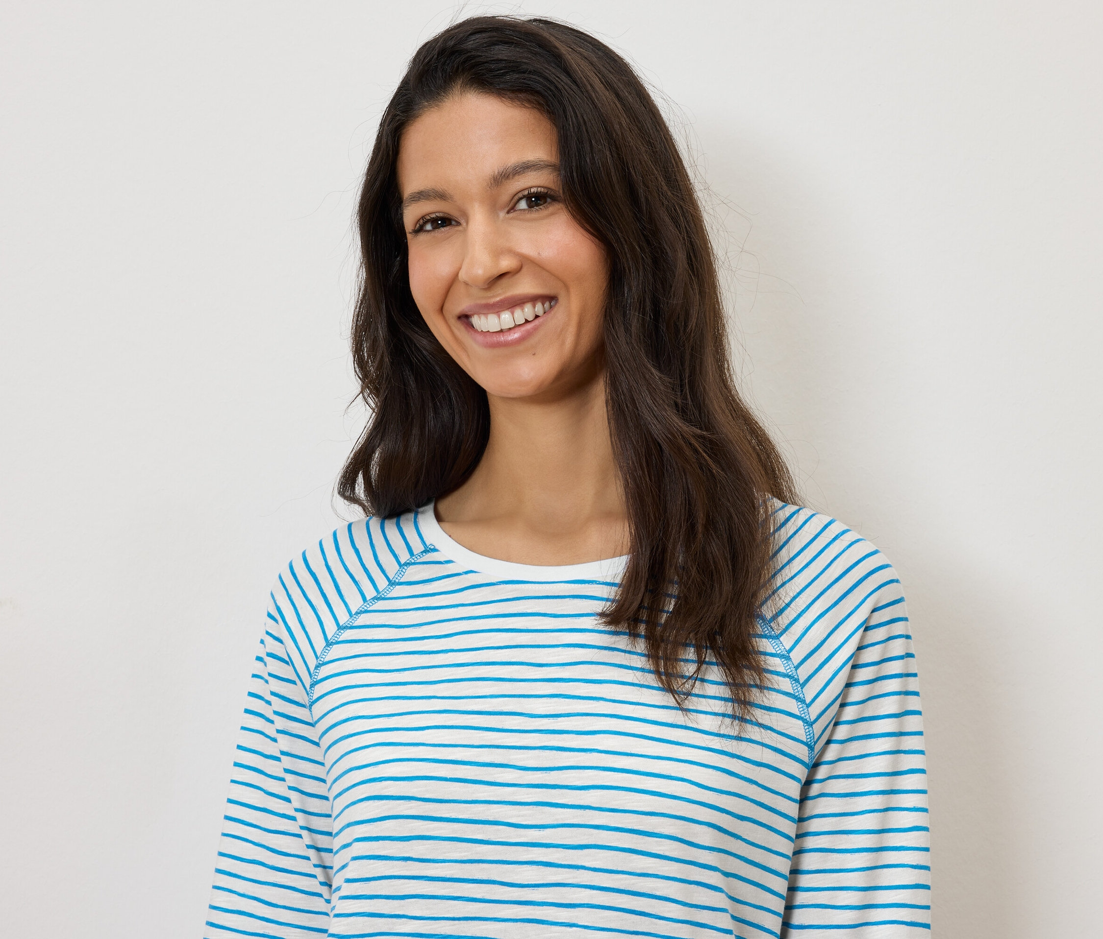 Uśmiechnięta kobieta w bluzce w biało-niebieskie paski na białym tle.