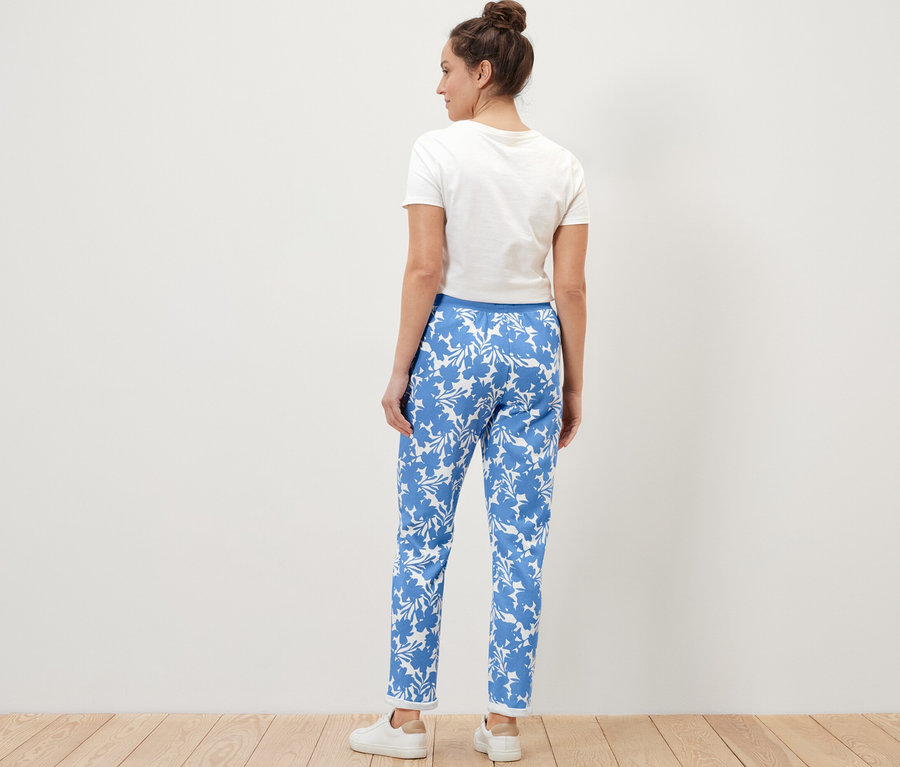 Kobieta stoi tyłem, ubrana we wzorzyste spodnie dresowe.