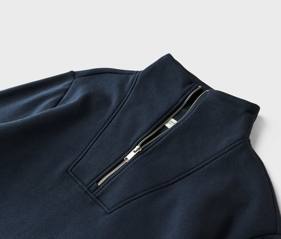 Zbliżenie granatowej bluzy dresowej z zamkiem błyskawicznym przy kołnierzu.
