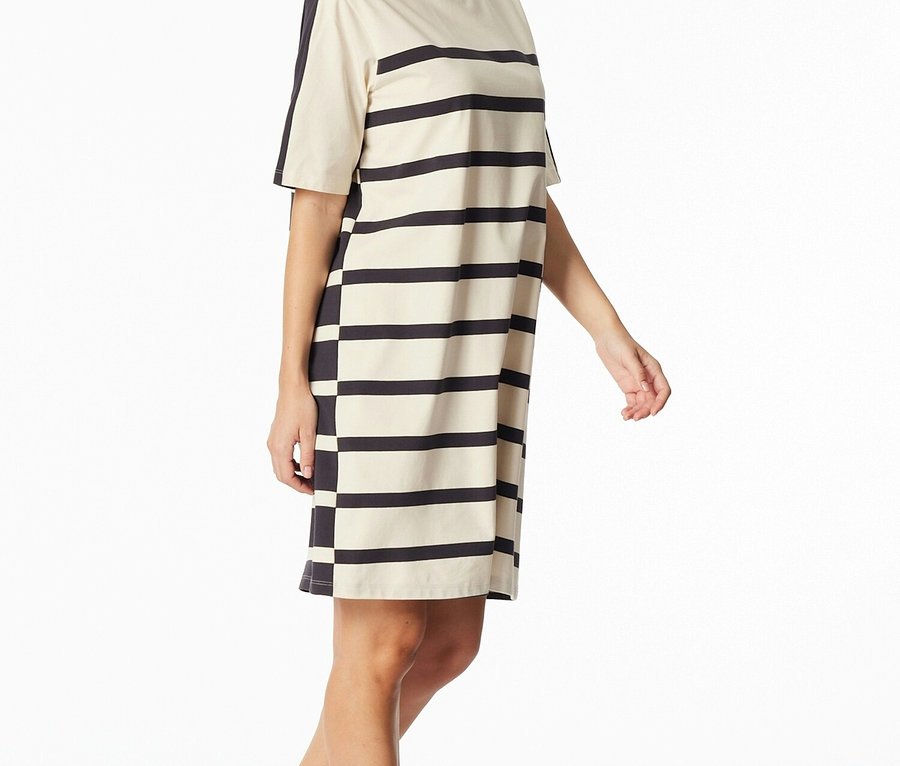 Kobieta ma na sobie krótki rękaw, sukienkę w paski w kolorze czarnym i kremowym.