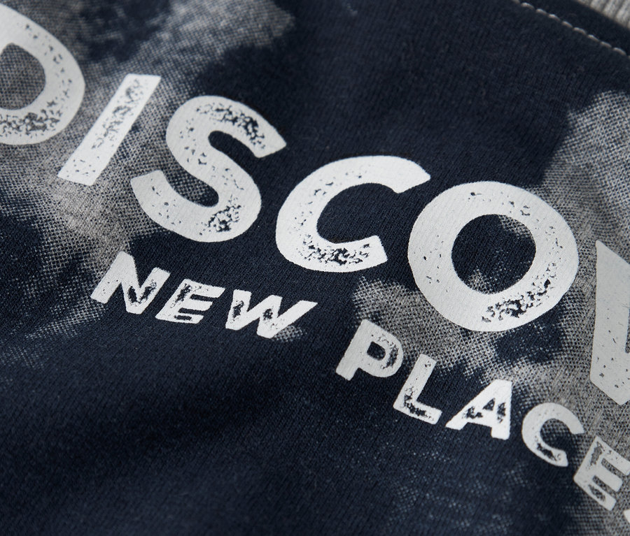 Zbliżenie na granatowy materiał z napisem "DISCOVER NEW PLACES".