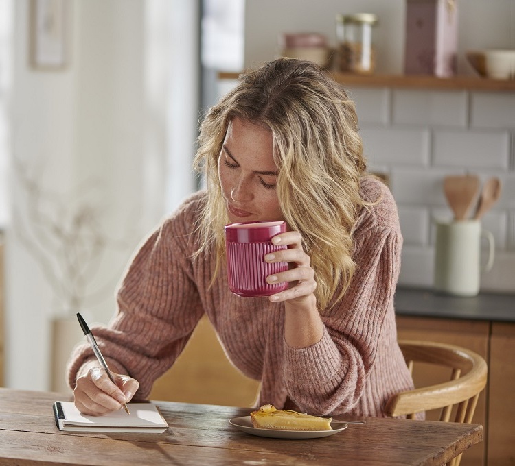 Eine Frau trinkt ihren Kaffee aus einem rosa Kaffeebecher der Porzellanserie.