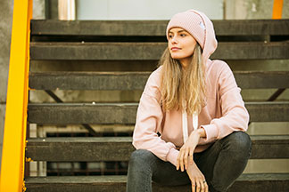 Bluza damska w połączeniu z czapką, dżinsami i sneakersami jako przykład luźnej i stylowej mody ulicznej.