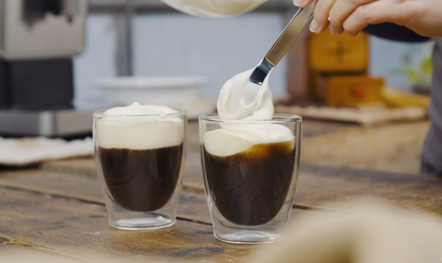 Zwei Kaffees werden mit cremigem Milchschaum bedeckt.
