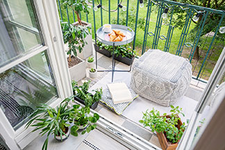Oszczędność miejsca: niewielki balkon z workiem do siedzenia i zielonymi roślinami, na którym stoi mały, okrągły stół ogrodowy.