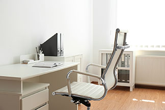 Nowoczesne, ergonomiczne krzesło biurowe z białym siedziskiem stoi przy białym biurku.